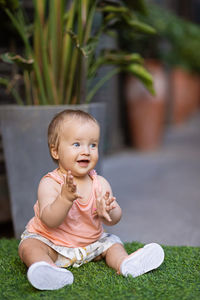 Cute baby girl looking away while sitting outdoors