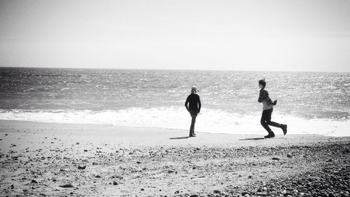 Children playing at beach against clear sky on sunny day