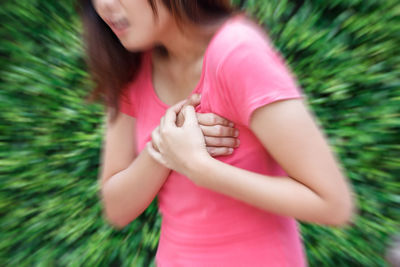 Midsection of woman with hands on chest suffering from heartache against plants