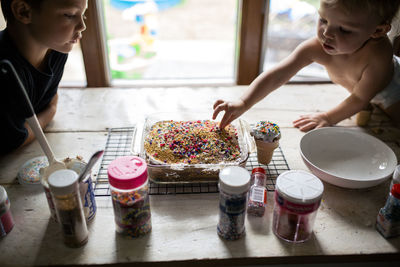 Little girl sneaking sprinkles off of freshly baked cake