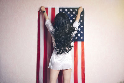 Rear view of woman standing against wall