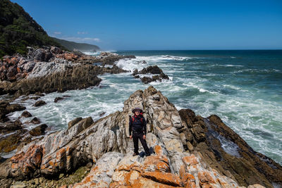 Full length of man on rock at beach against sky