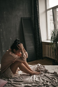 Woman sitting on bed at home