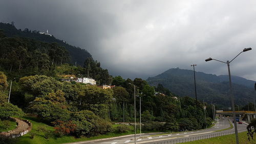 Road by trees against sky