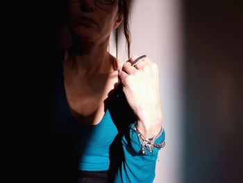 Midsection of woman sitting against wall at home