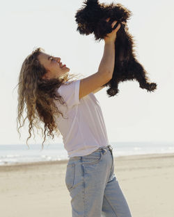 Side view of woman with arms outstretched standing at beach