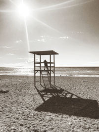 Lifeguard hut on beach against sky on sunny day