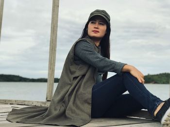 Beautiful young woman sitting on pier 