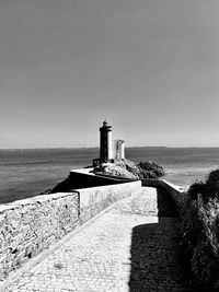 Lighthouse by sea against clear sky