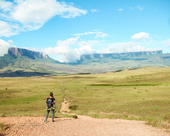 Rear view of woman walking on landscape against sky