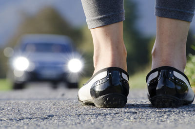 Low section of woman standing on road