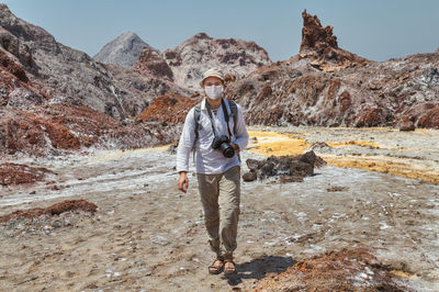 Full length portrait of young man standing on rock