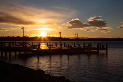 Silhouette pier over sea against sky during sunset