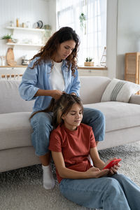 Mother and daughter sitting on sofa at home