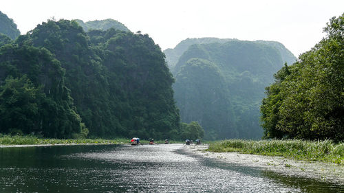 Scenic view of river by trees against mountain