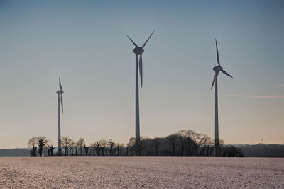 Wind turbines against sky during sunset