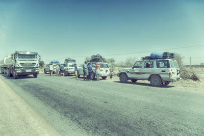 Vehicles on road against clear sky in city