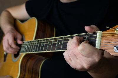 Midsection of man playing guitar