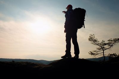 Silhouette man standing on mountain against sky during sunset