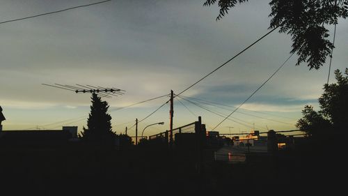 Low angle view of power lines against cloudy sky