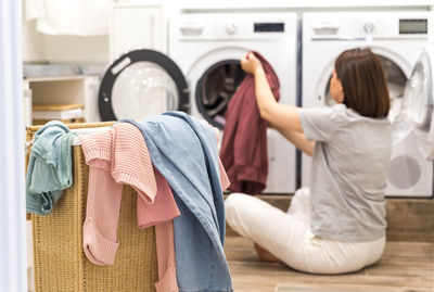 Rear view of woman removing clothes from washing machine