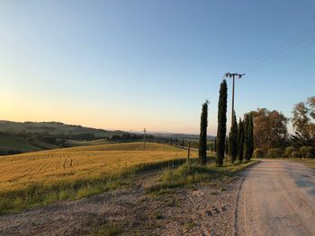 Road amidst field against clear sky