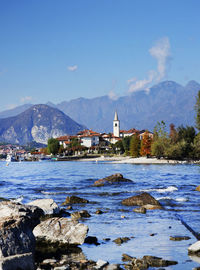 Scenic view of buildings by mountains against sky