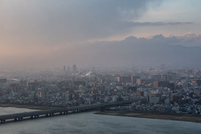 Illuminated buildings in city against sky at sunset