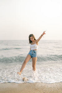 Full length of young woman standing at beach