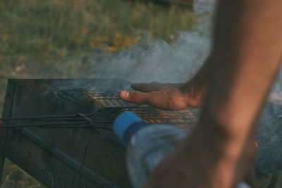 Cropped hands of man over barbecue grill