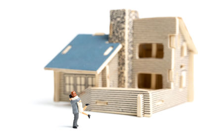 Close-up of couple figurine with model home over white background