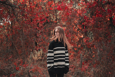 Rear view of woman standing against trees during autumn