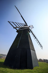 Low angle view of traditional windmill on field against sky