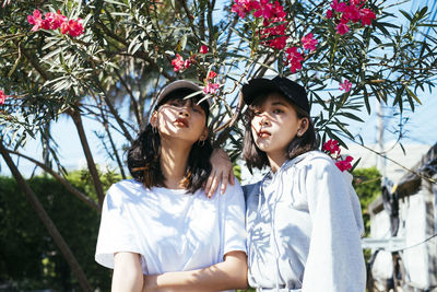 Portrait of friends standing against flowering plants