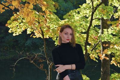 Portrait of young woman standing against plants