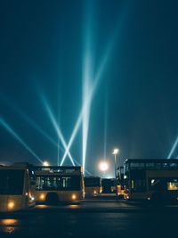 Buses on illuminated road against sky at night