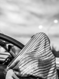 Rear view of woman with scarf standing against sky