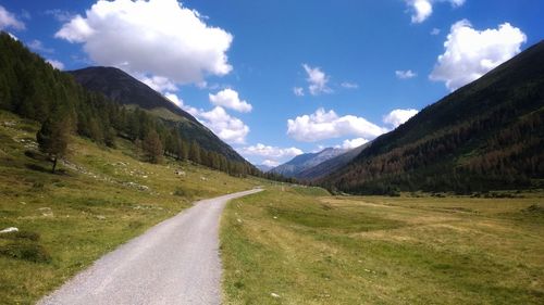 Road leading towards mountains against sky