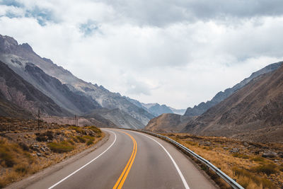 Empty road by mountains against sky