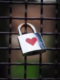 Close-up of heart shape on padlock hanging from railing
