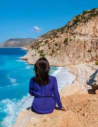 Rear view of woman looking at sea against clear blue sky