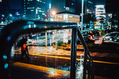 Reflection of illuminated city on wet road at night