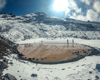 Scenic view of snow covered mountains against bright sun