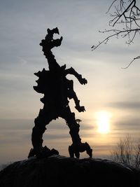 Silhouette rock on tree against sky during sunset