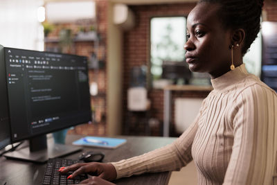 Side view of young man using laptop in office