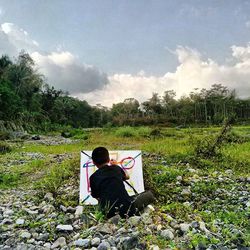 Rear view of man sitting on grass