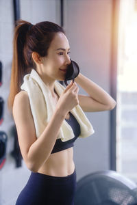 Side view of young woman holding camera while standing in office