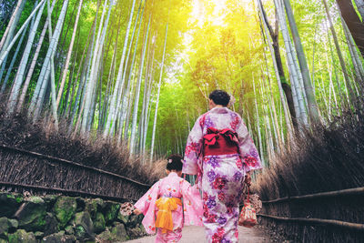 Rear view of people walking on road in forest