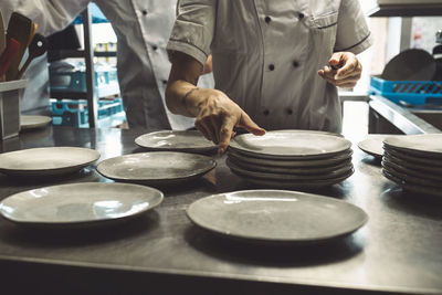 Midsection of chef arranging plates at kitchen counter