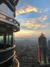 Modern buildings in city against sky during sunset